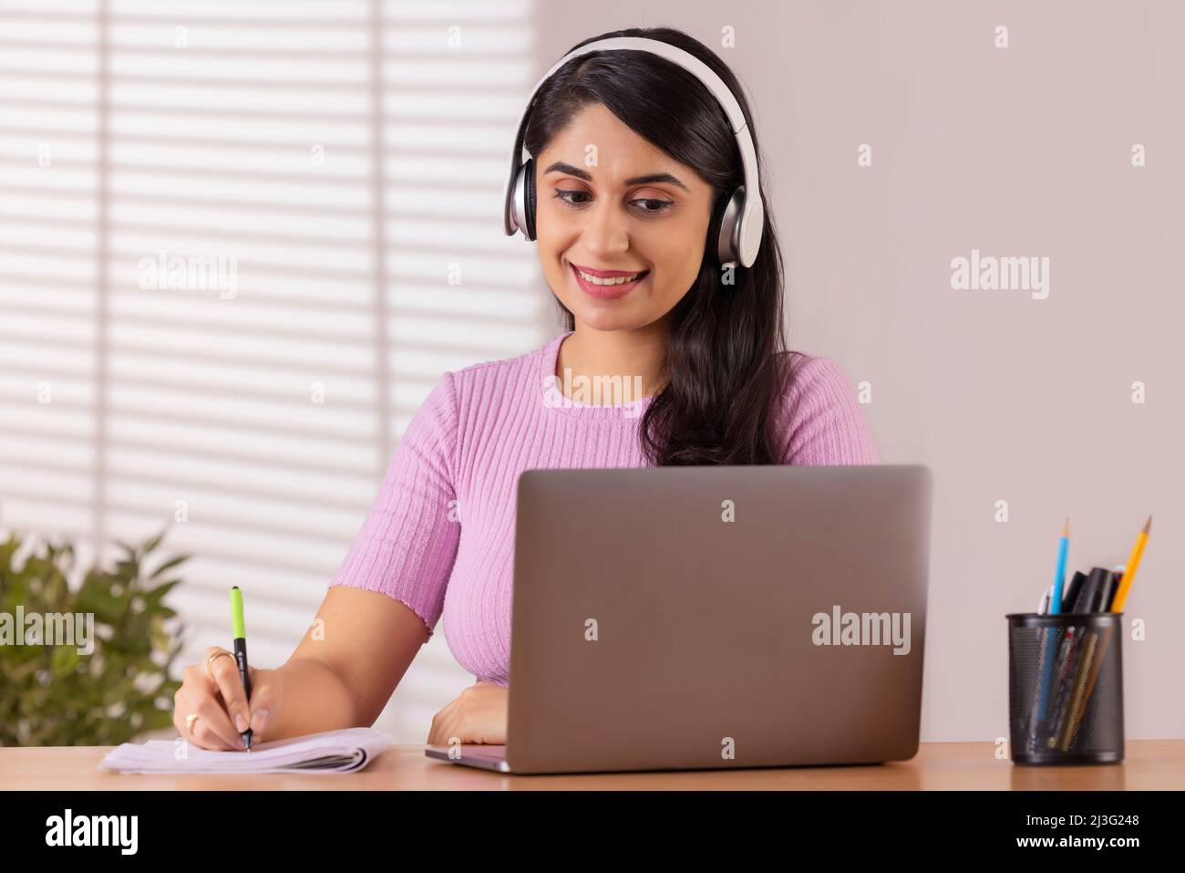 Une jeune femme de direction écrit sur un ordinateur portable lors d'une vidéoconférence au bureau Banque D'Images