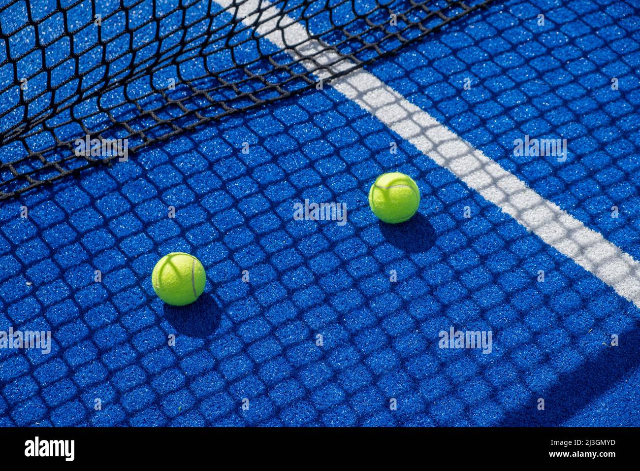 deux balles de paddle-tennis à l'ombre du filet d'un court de paddle-tennis bleu, concept de sports de raquette Banque D'Images