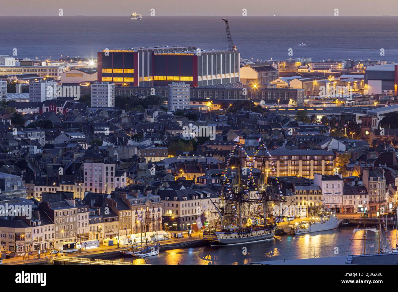France, Manche, Cotentin, Cherbourg-Octeville, frégate d'Hermione amarré au bassin du Commerce au lever du soleil et bâtiment principal de la cour d'assemblage militaire sous-marine du Groupe naval Banque D'Images