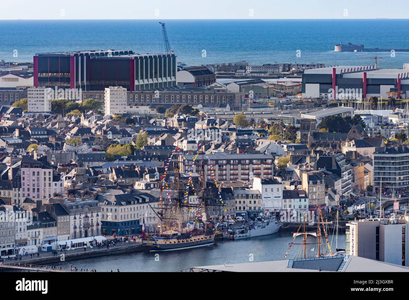 France, Manche, Cotentin, Cherbourg-Octeville, frégate d'Hermione ancré dans le bassin du Commerce et bâtiment principal de la cour d'assemblage militaire sous-marine du Groupe naval Banque D'Images