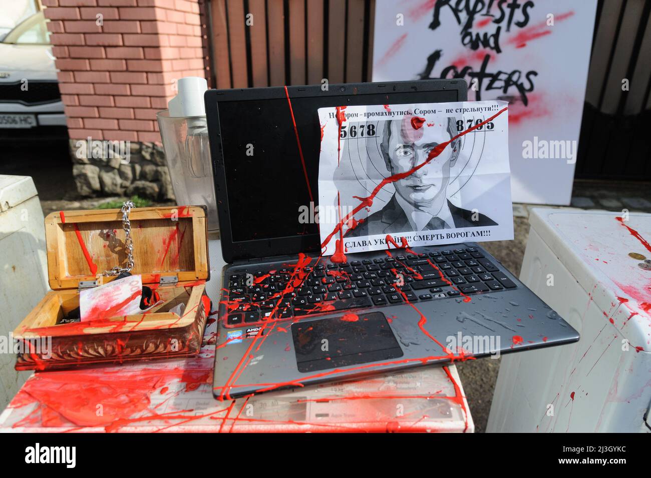 Lviv, Ukraine. 08th avril 2022. Un ordinateur portable avec le portrait de Vladimir Poutine, des pièces d'équipement de bureau et des appareils ménagers symbolisant ceux que les soldats russes ont volé dans les territoires occupés ukrainiens, flatté de peinture rouge au Consulat de la Fédération de Russie lors d'une protestation "l'armée russe - est une foule de meurtriers, violeurs et pleurs". Crédit : SOPA Images Limited/Alamy Live News Banque D'Images