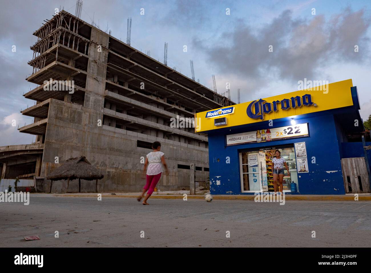 Mexique, Etat d'Oaxaca, Puerto Escondido et sa plage, la Punta Zicatela, deux jeunes jouent devant une épicerie et devant un hôtel en construction et s'arrêtent parce qu'ils sont construits sans permis de construire légal Banque D'Images