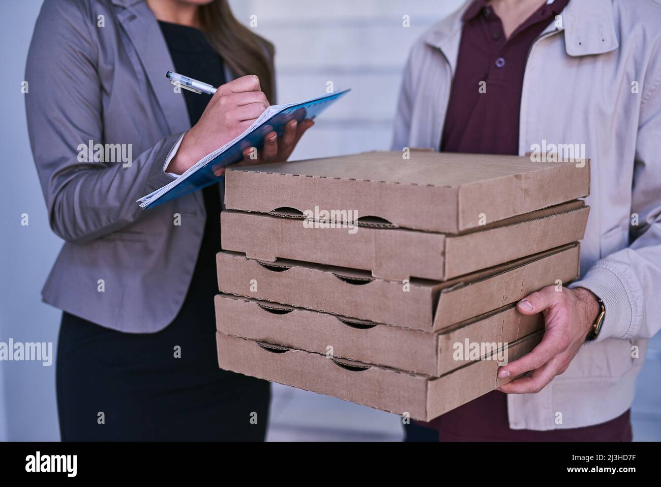 Si frais, sa tuyauterie encore chaude. Plan court d'un homme qui fait une livraison de pizza à une femme d'affaires au travail. Banque D'Images