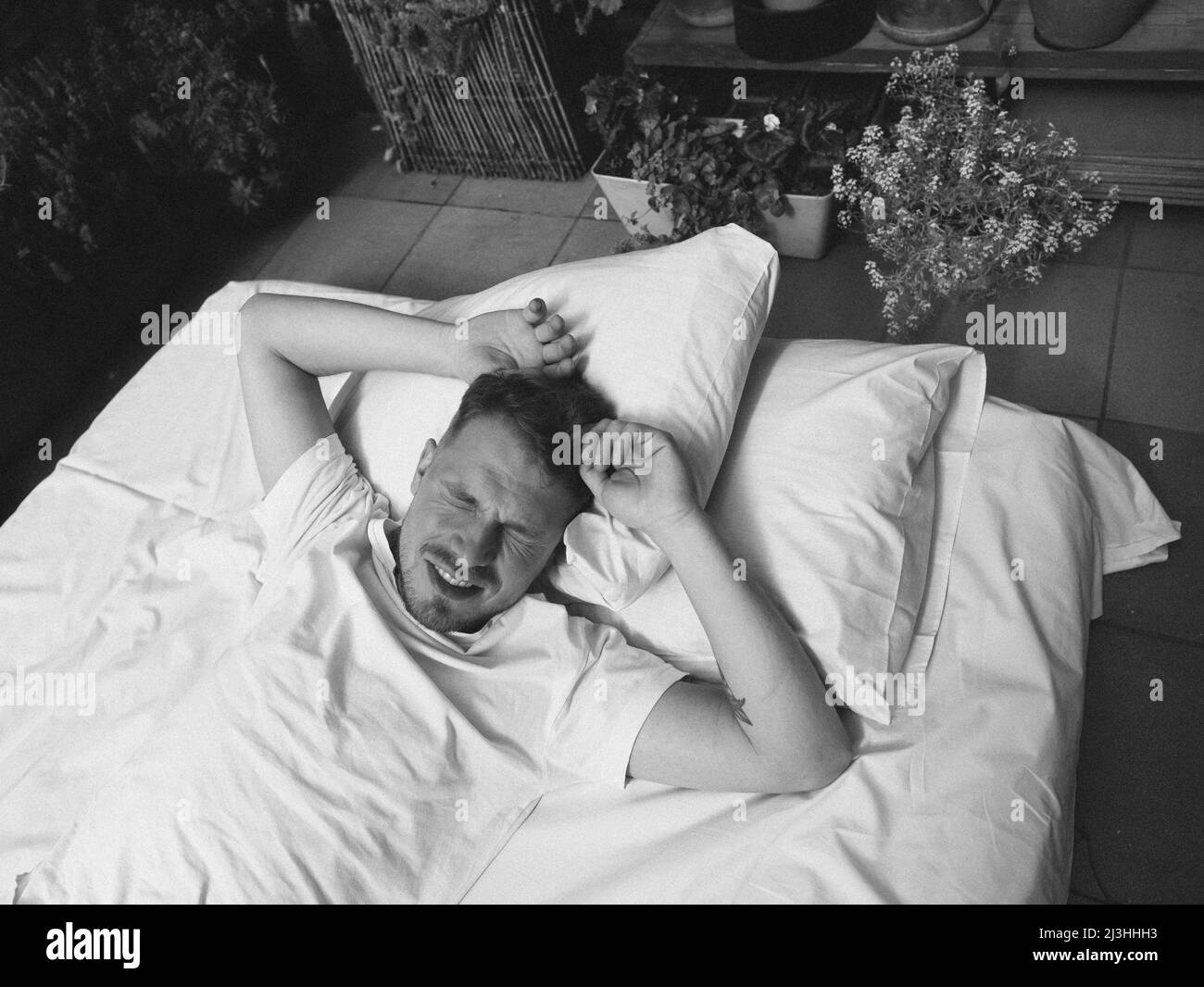 Homme dormant sur le lit dans la chambre à la maison à l'effet de grain blond Banque D'Images