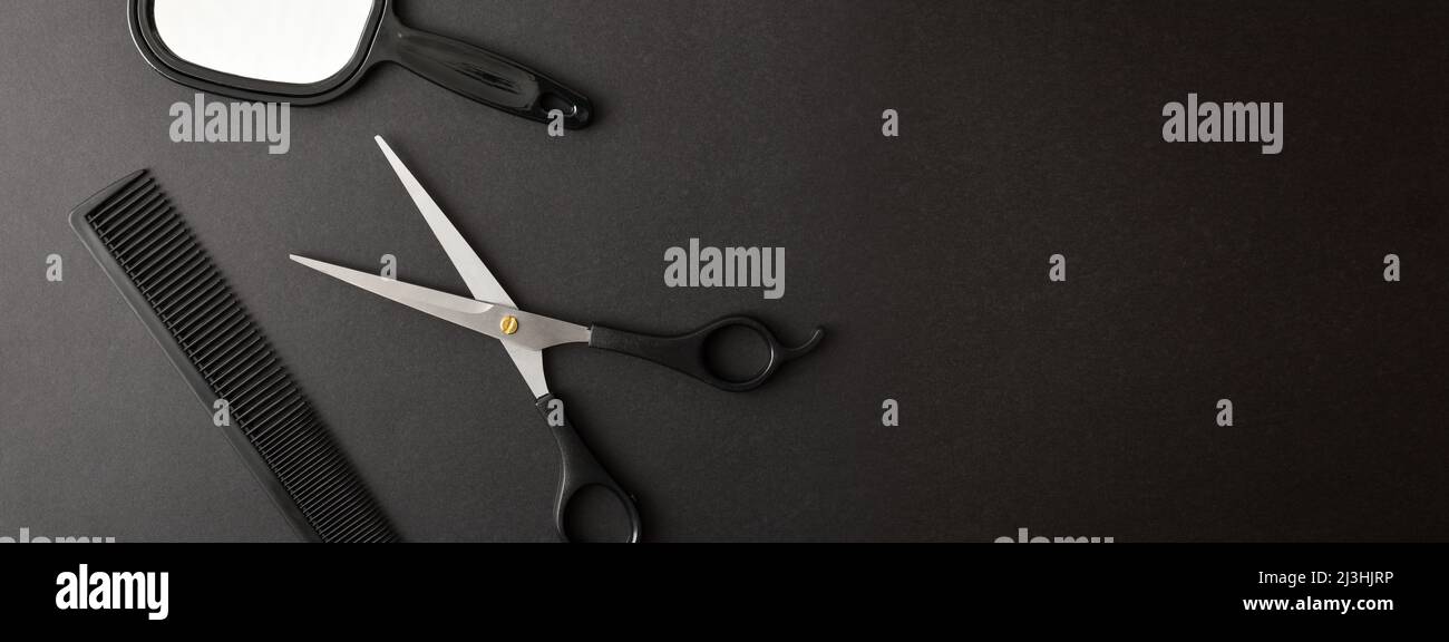 Arrière-plan conceptuel de base de la coiffure avec peigne de ciseaux et miroir sur fond noir et espace pour écrire. Vue de dessus. Composition horizontale. Banque D'Images