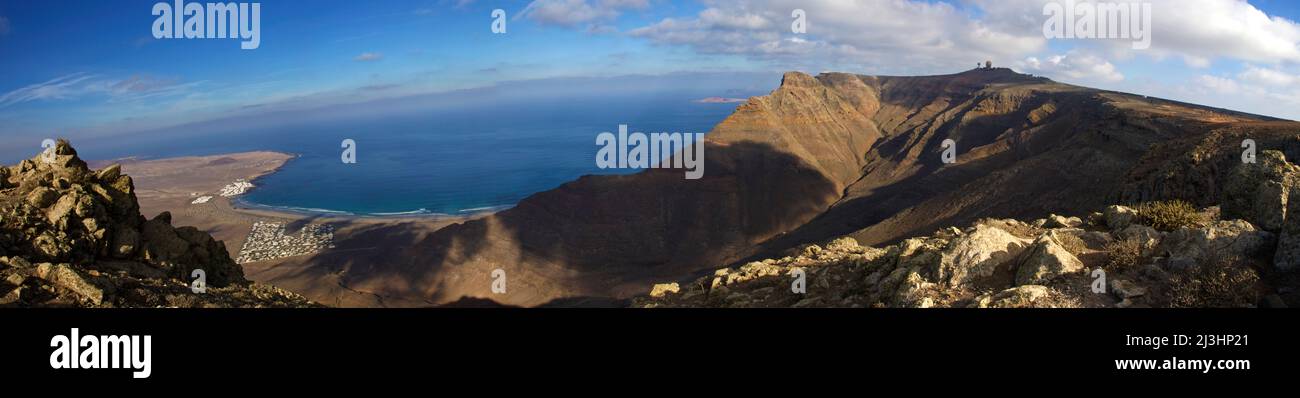 Îles Canaries, Lanzarote, île volcanique, côte nord-ouest, ermitage, eglise, Ermita de las Nieves, bleu ciel, prise de vue panoramique à 180°, pic rocheux gauche, au milieu de la vue vers le bas de la côte ouest, vue à droite sur le mur de roche, sur lui un dôme radar, bleu ciel, nuages blancs Banque D'Images