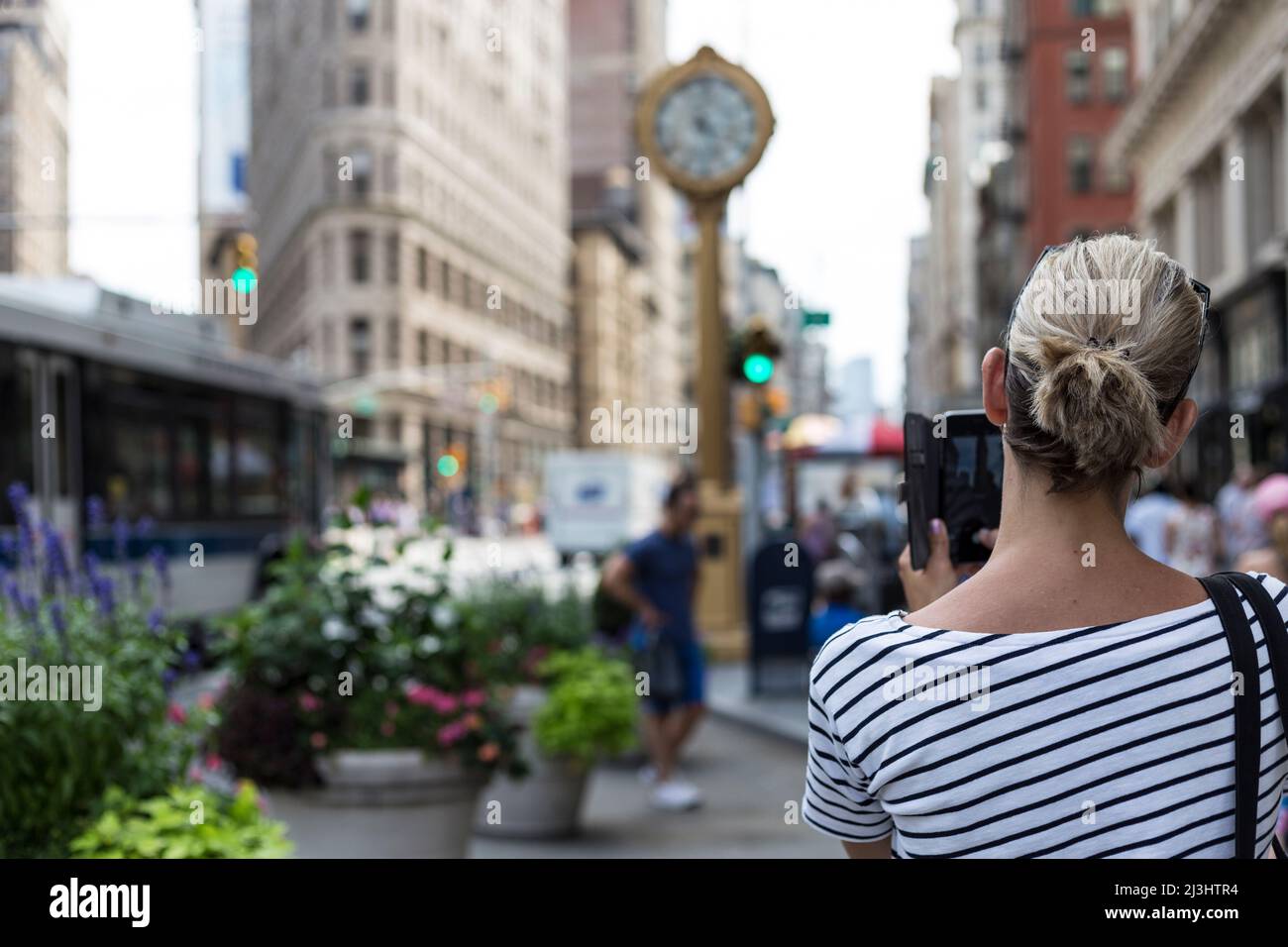 5th AV & W 23rd Street, New York City, NY, Etats-Unis, Une femme blonde filant le bâtiment flatiron avec son smartphone Banque D'Images