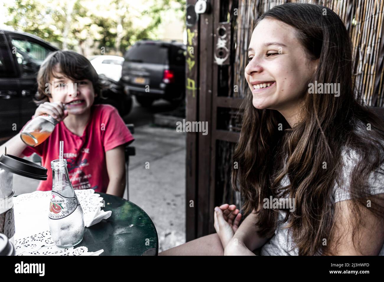 Bushwick, New York City, NY, États-Unis, jeune fille de 14 ans de race blanche et adolescent de race blanche de 12 ans, tous deux avec des cheveux bruns et un style d'été dans un café Banque D'Images