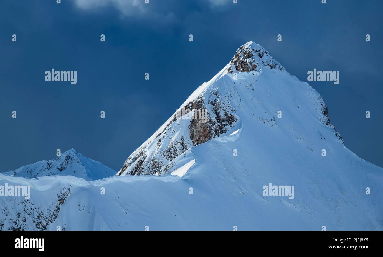 Le pic enneigé de la montagne se fait trembler par le soleil devant les nuages sombres. Arrowhead, Alpes de Lechtal, Tyrol, Autriche Banque D'Images