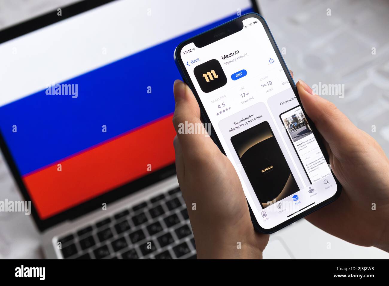 Poltava, Ukraine - 8 avril 2022 : la femme utilise l'application Meduza, arrière-plan du drapeau russe. Application de nouvelles bloquée en Fédération de Russie, téléphone mobile avec ico Banque D'Images