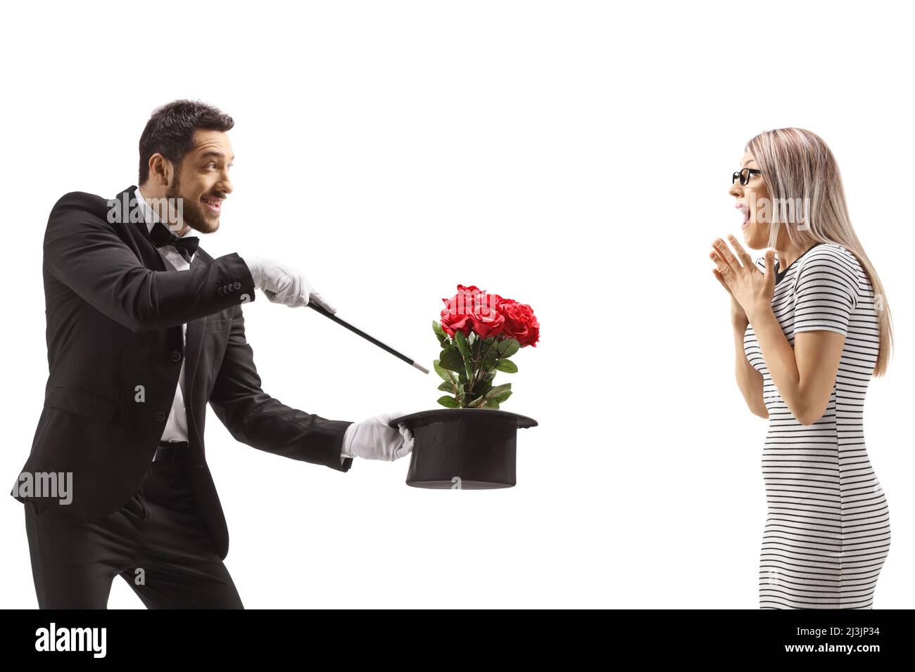 Magicien faisant un tour magique avec des fleurs et un chapeau devant une femme surprise isolée sur fond blanc Banque D'Images