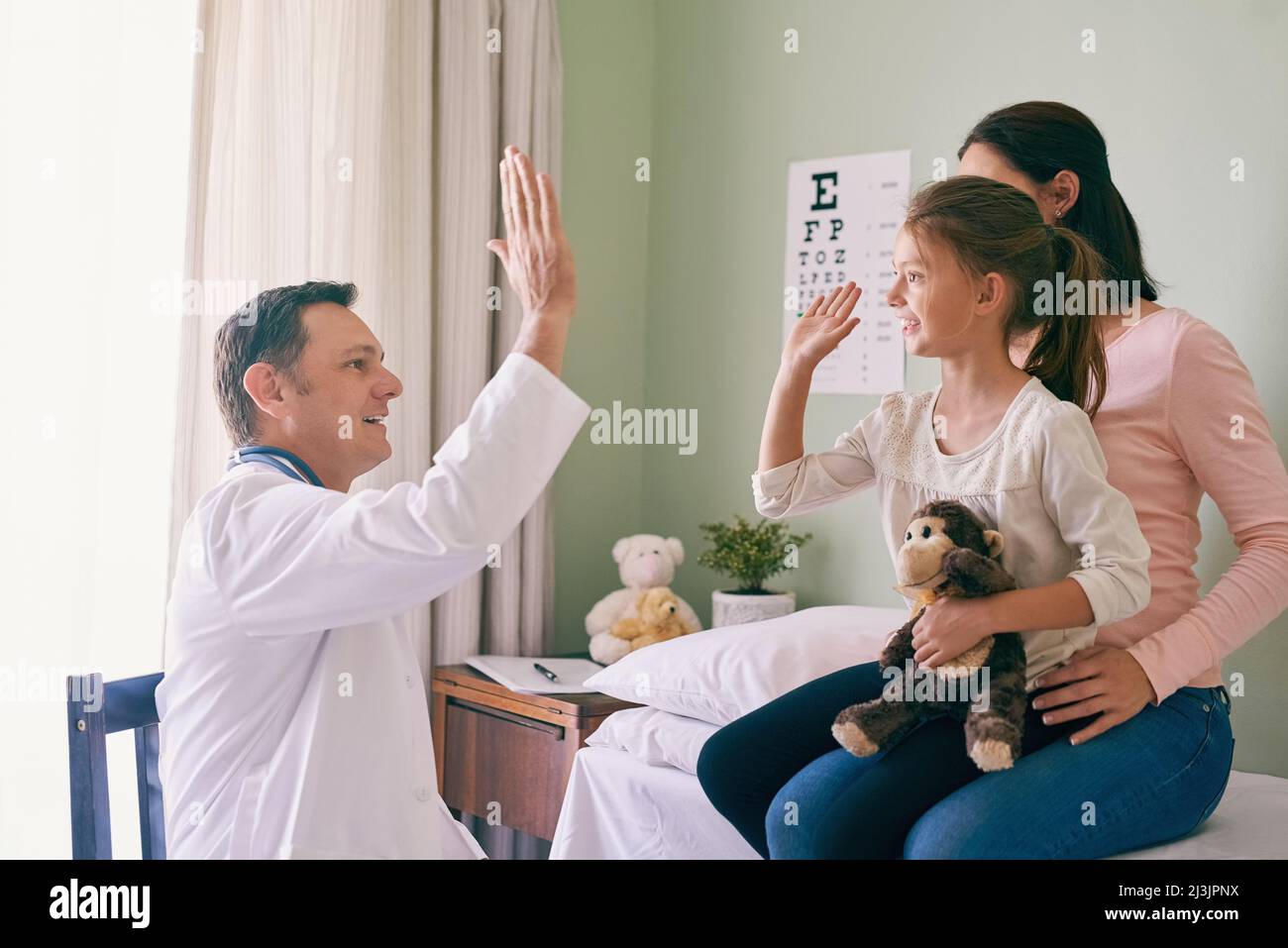 Cinq hauts pour une petite fille courageuse. Prise de vue d'un médecin donnant à son jeune patient un haut cinq après son examen. Banque D'Images