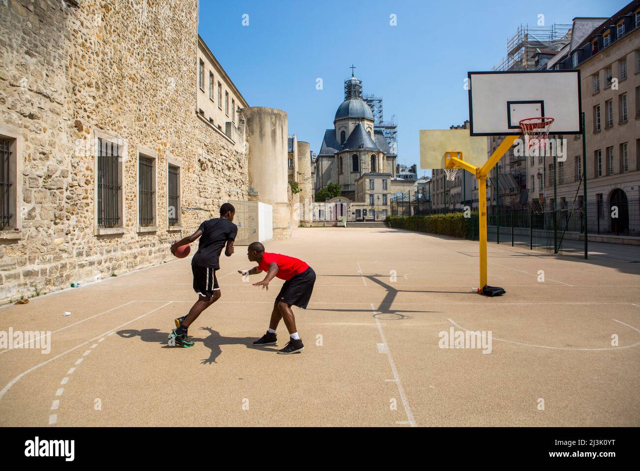 Les jeunes jouent au basket-ball dans la cour derrière l'église Saint-Paul Saint-Louis située dans le Marais, Paris, France, Paris, France Banque D'Images
