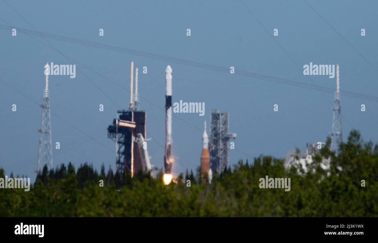 Floride, États-Unis. 08th avril 2022. NASAs la fusée SLS (Space Launch System) à bord de l'engin spatial Orion est vue au sommet d'un lanceur mobile au Launch Complex 39B, à droite, En tant que fusée SpaceX Falcon 9 transportant le vaisseau spatial Crew Dragon de la société est lancé sur Axiom Mission 1 (axe-1) à la Station spatiale internationale avec le commandant Michael López-Alegría d'Espagne et des États-Unis, le pilote Larry Connor des États-Unis, et les spécialistes de mission Eytan Stibbe d'Israël, Et Mark Pathy du Canada à bord, le vendredi 8 avril 2022, au Centre spatial NASAs Kennedy en Floride. La mission Ax-1 est la première pr Banque D'Images