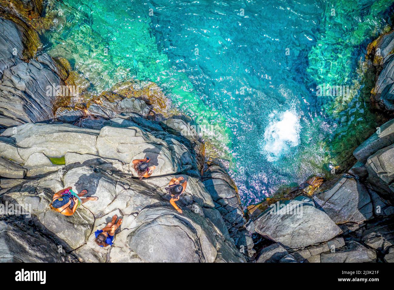 Vue de drone des touristes se tenant au sommet d'une grande falaise de roche se préparant à sauter à l'eau en dessous; Kapalua, Maui, Hawaii, États-Unis d'Amérique Banque D'Images