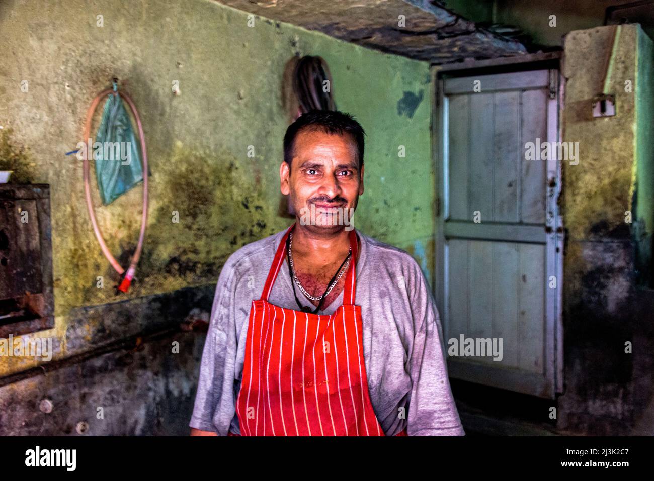 Homme mature portant un tablier dans une cuisine en Inde; Amritsar, Punjab, Inde Banque D'Images