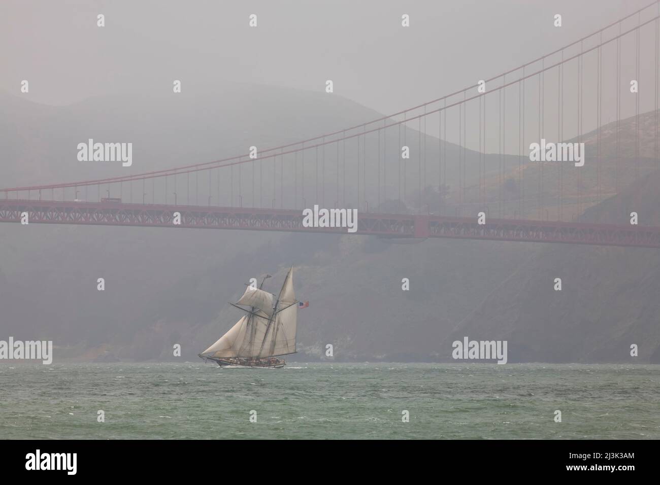 Une goélette à deux mâts navigue sous le Golden Gate Bridge; San Francisco, Californie. Banque D'Images