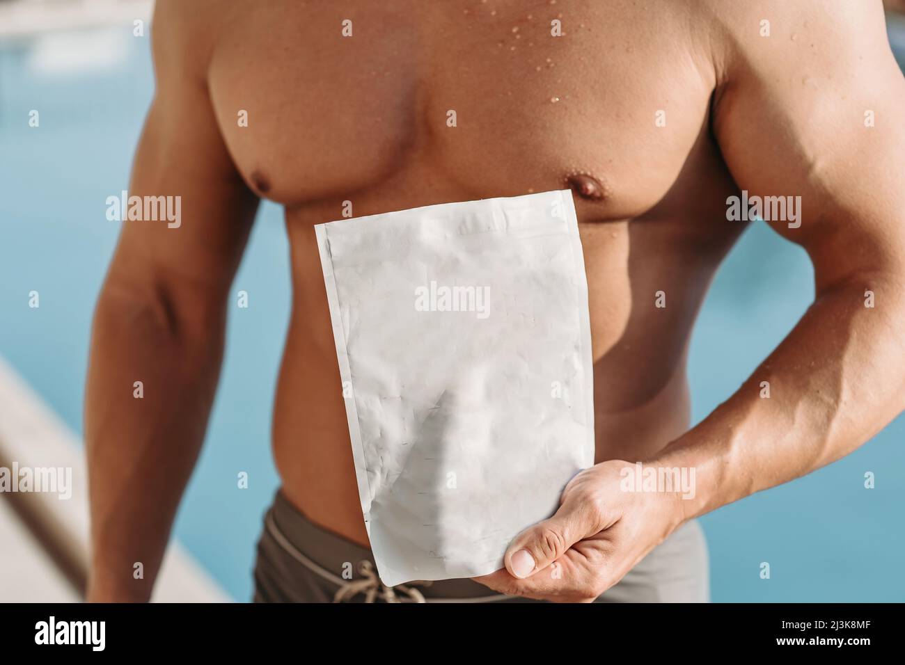 L'athlète avec de gros muscles tient un paquet de nutrition sportive Banque D'Images