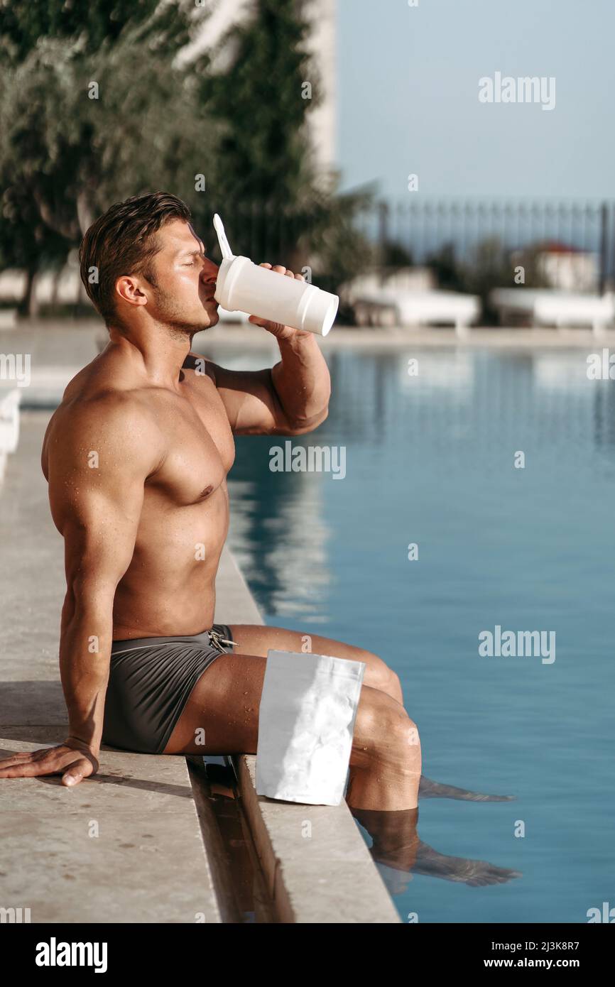 Un jeune homme avec de gros muscles boit un cocktail de protéines Banque D'Images