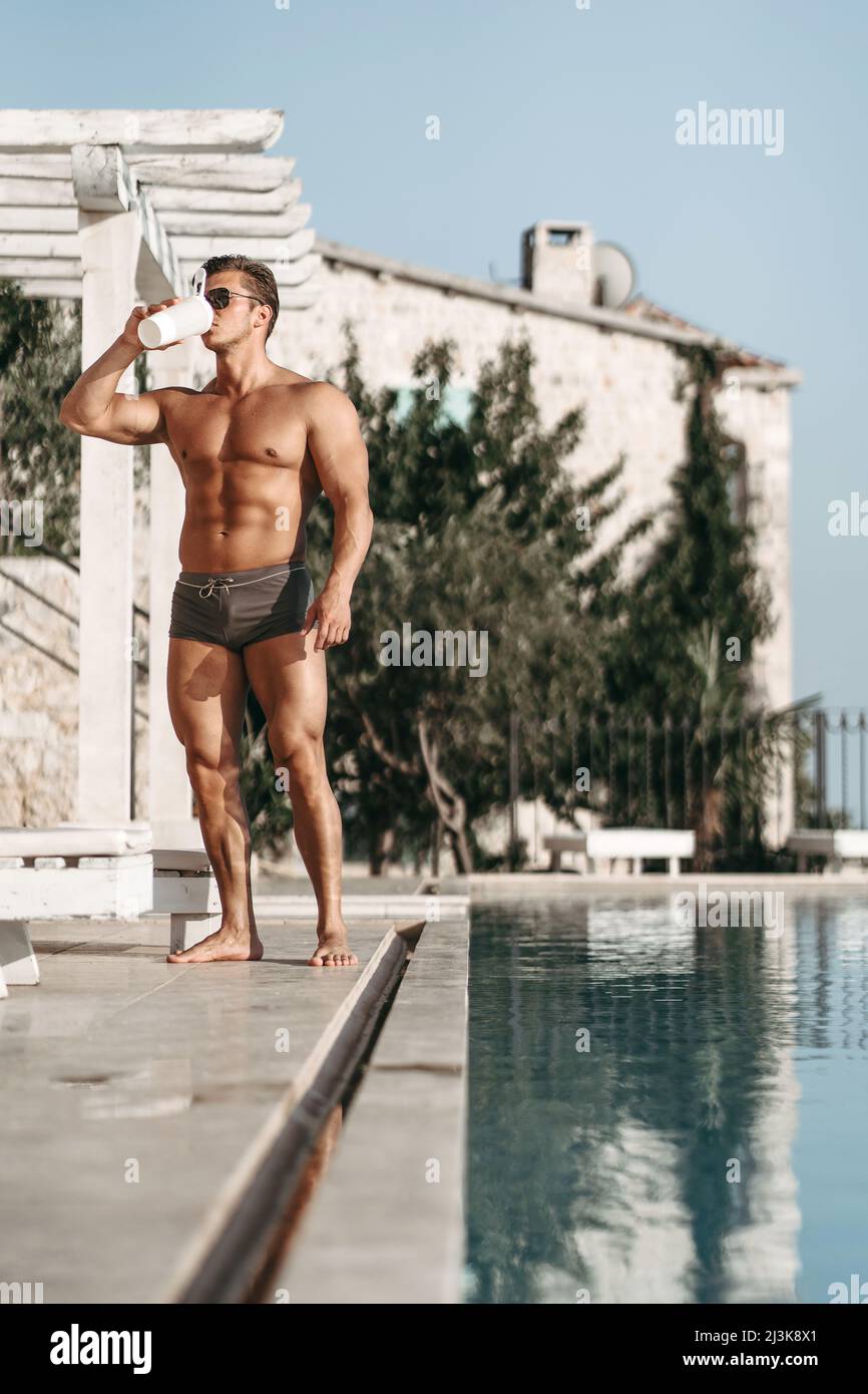 Un jeune homme avec de gros muscles boit un cocktail de protéines Banque D'Images