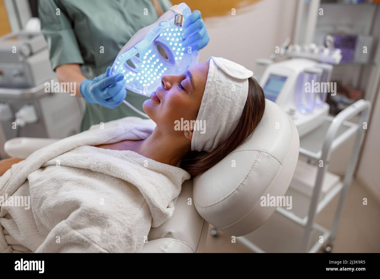 Femme qui obtient une procédure cosmétique avec un masque facial LED. Photonthérapie Banque D'Images Femme qui obtient une procédure cosmétique avec un masque facial LED. Photonthérapie Banque D'Images