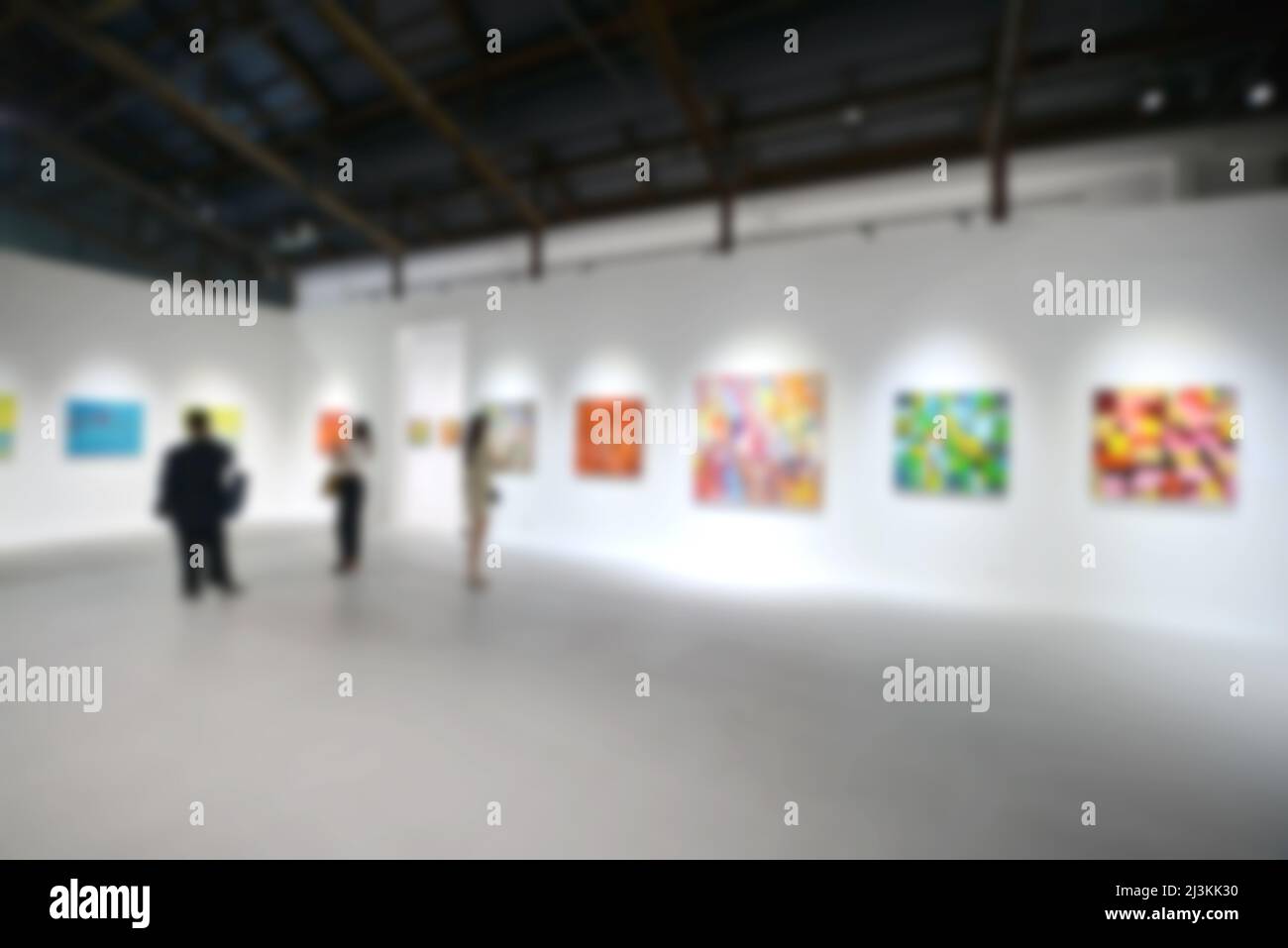 Personnes regardant des peintures sur le mur blanc dans la galerie d'exposition d'art. Arrière-plan flou. Banque D'Images
