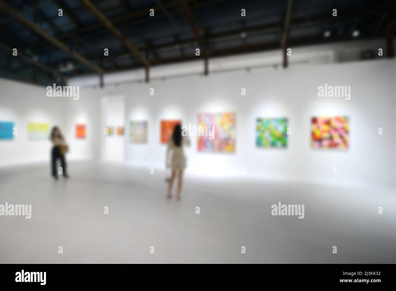 Personnes regardant des peintures sur le mur blanc dans la galerie d'exposition d'art. Arrière-plan flou. Banque D'Images