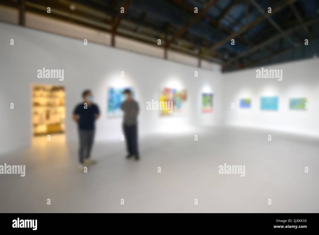 Personnes regardant des peintures sur le mur blanc dans la galerie d'exposition d'art. Arrière-plan flou. Banque D'Images