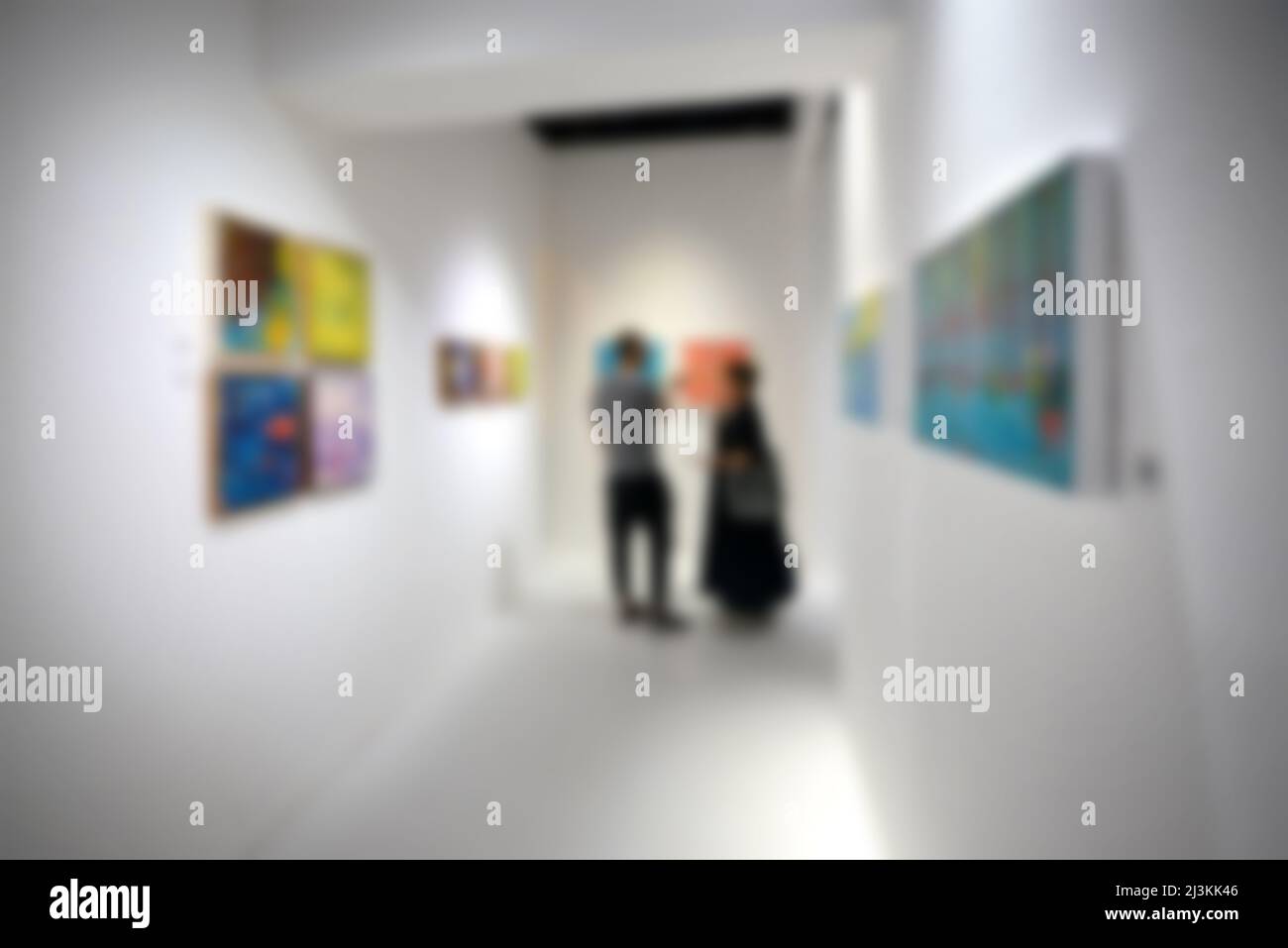 Personnes regardant des peintures sur le mur blanc dans la galerie d'exposition d'art. Arrière-plan flou. Banque D'Images