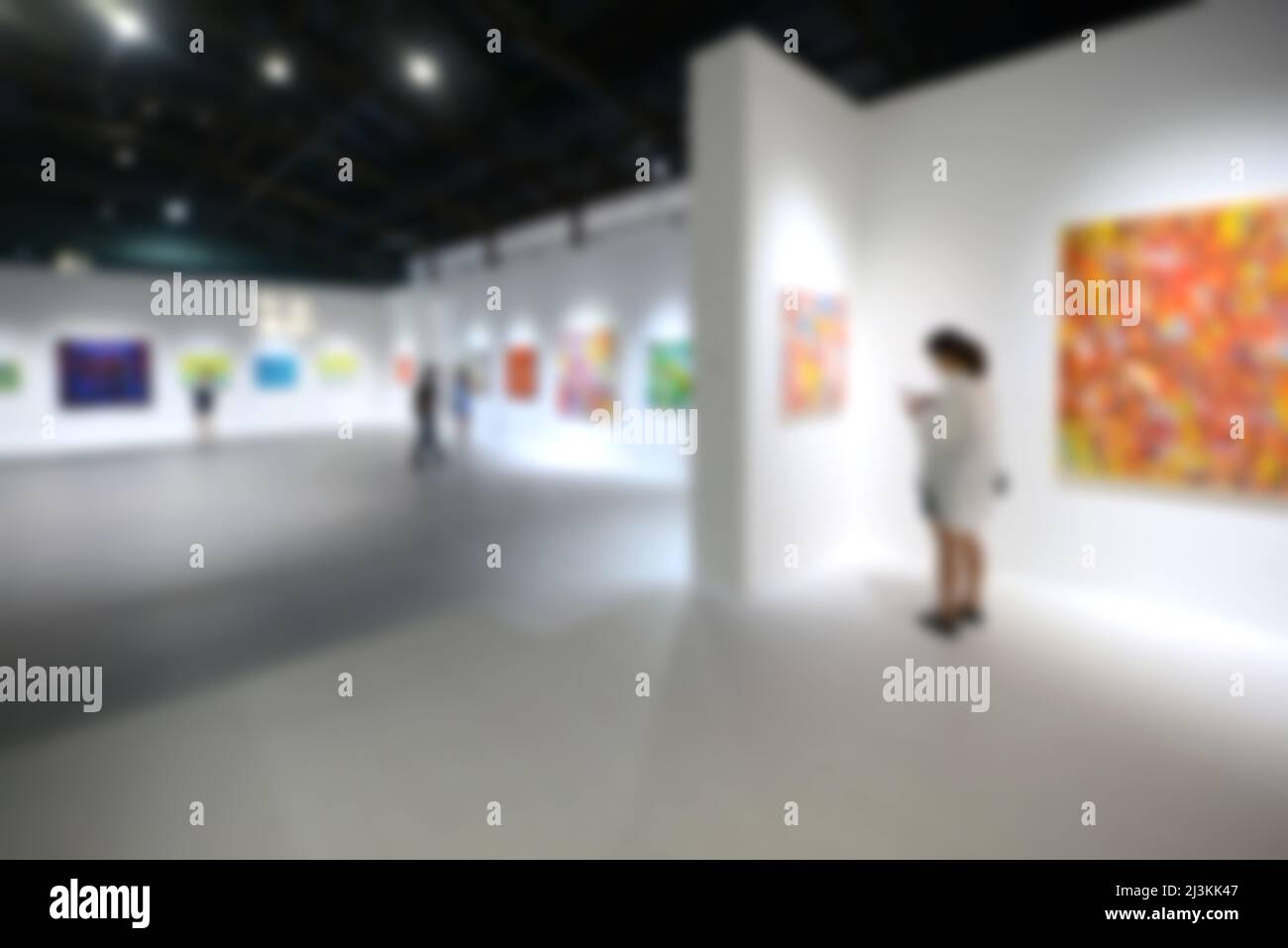 Personnes regardant des peintures sur le mur blanc dans la galerie d'exposition d'art. Arrière-plan flou. Banque D'Images