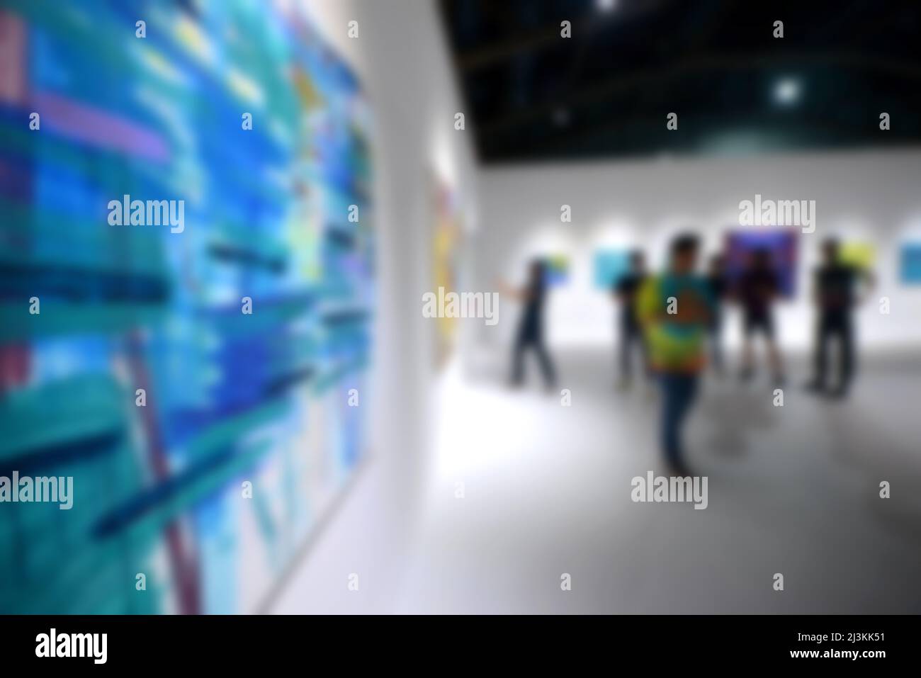 Personnes regardant des peintures sur le mur blanc dans la galerie d'exposition d'art. Arrière-plan flou. Banque D'Images