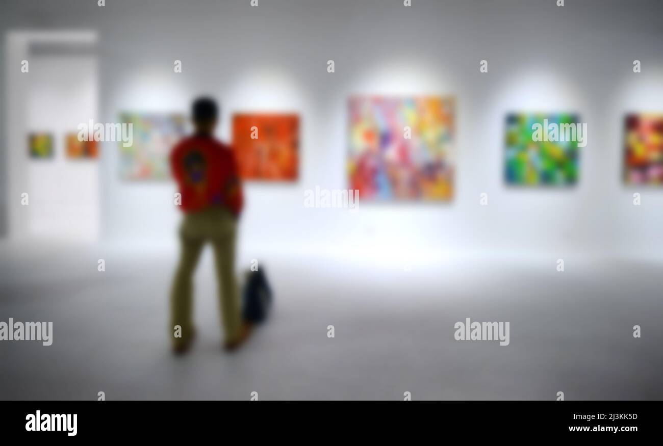 Personnes regardant des peintures sur le mur blanc dans la galerie d'exposition d'art. Arrière-plan flou. Banque D'Images