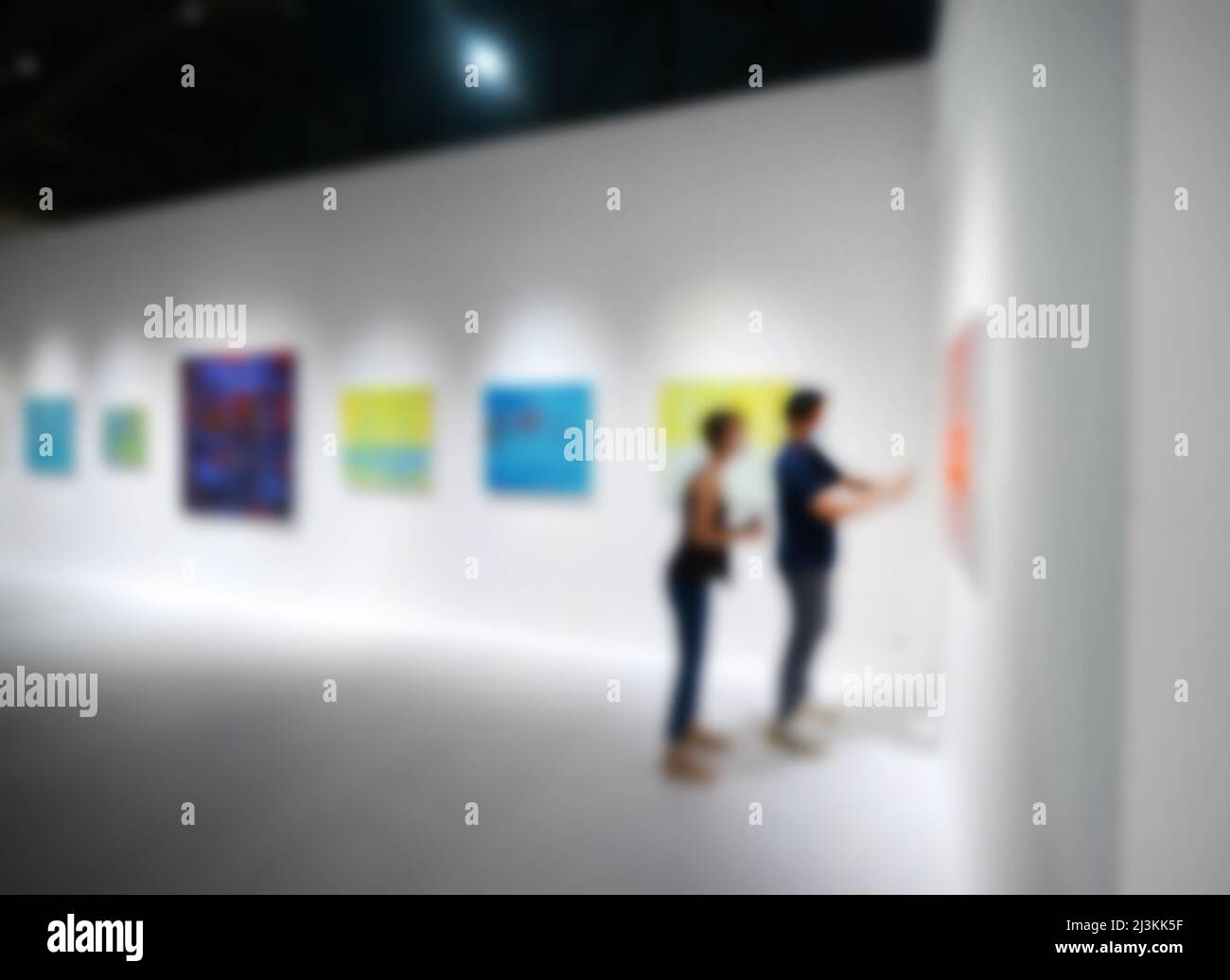 Personnes regardant des peintures sur le mur blanc dans la galerie d'exposition d'art. Arrière-plan flou. Banque D'Images