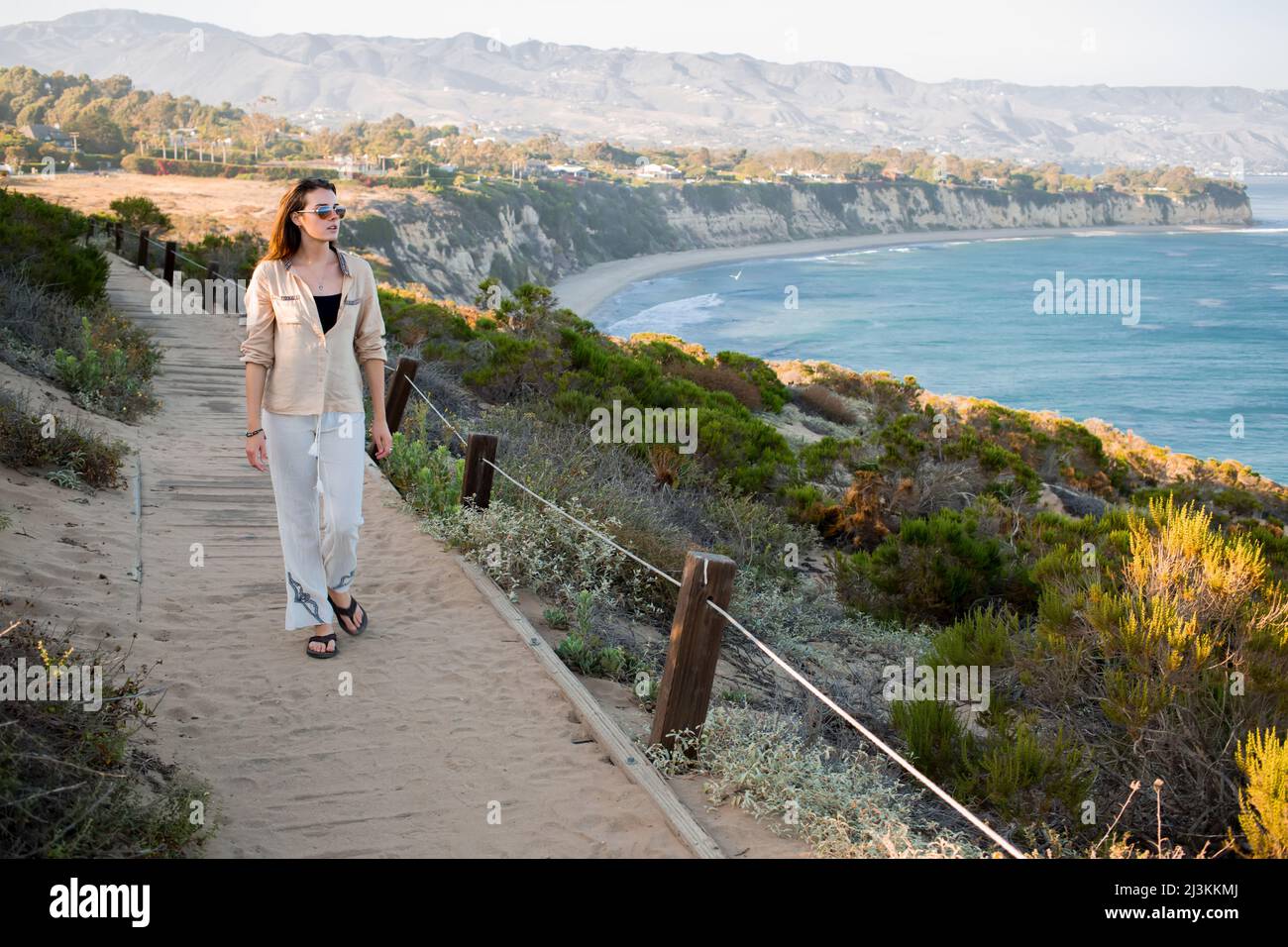 Une jeune femme marche sur un sentier au-dessus de la plage à point Dume. Banque D'Images
