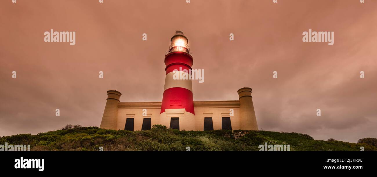 Phare de Cape Agulhas illuminé au crépuscule, parc national d'Agulhas; Cape Agulhas, Cap occidental, Afrique du Sud Banque D'Images