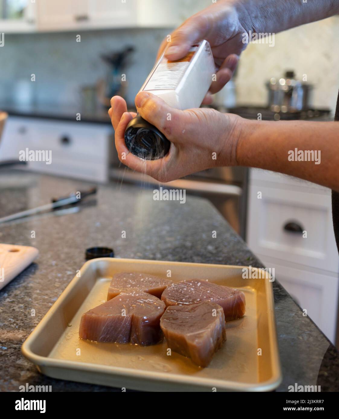 Verser des épices sur de la viande crue pour préparer la cuisine; Kelowna, Colombie-Britannique, Canada Banque D'Images