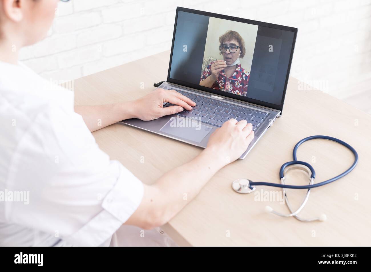 Une femme âgée avec la grippe pour une consultation en ligne avec un médecin. Une femme praticienne passe un appel vidéo avec un patient sur un ordinateur portable. Un retraité Banque D'Images