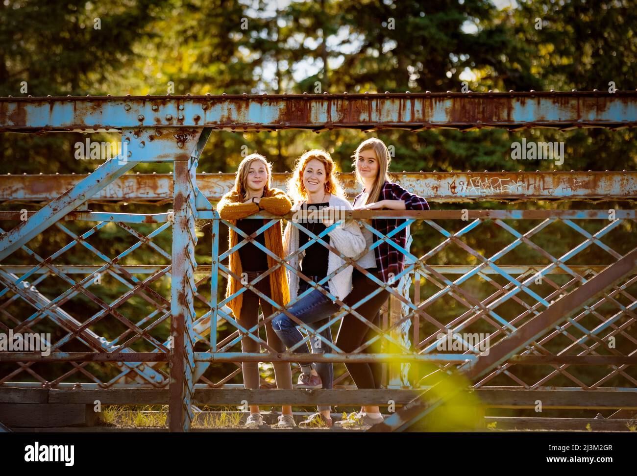 Portrait extérieur d'une mère avec deux filles debout sur un pont dans un parc municipal; Edmonton, Alberta, Canada Banque D'Images