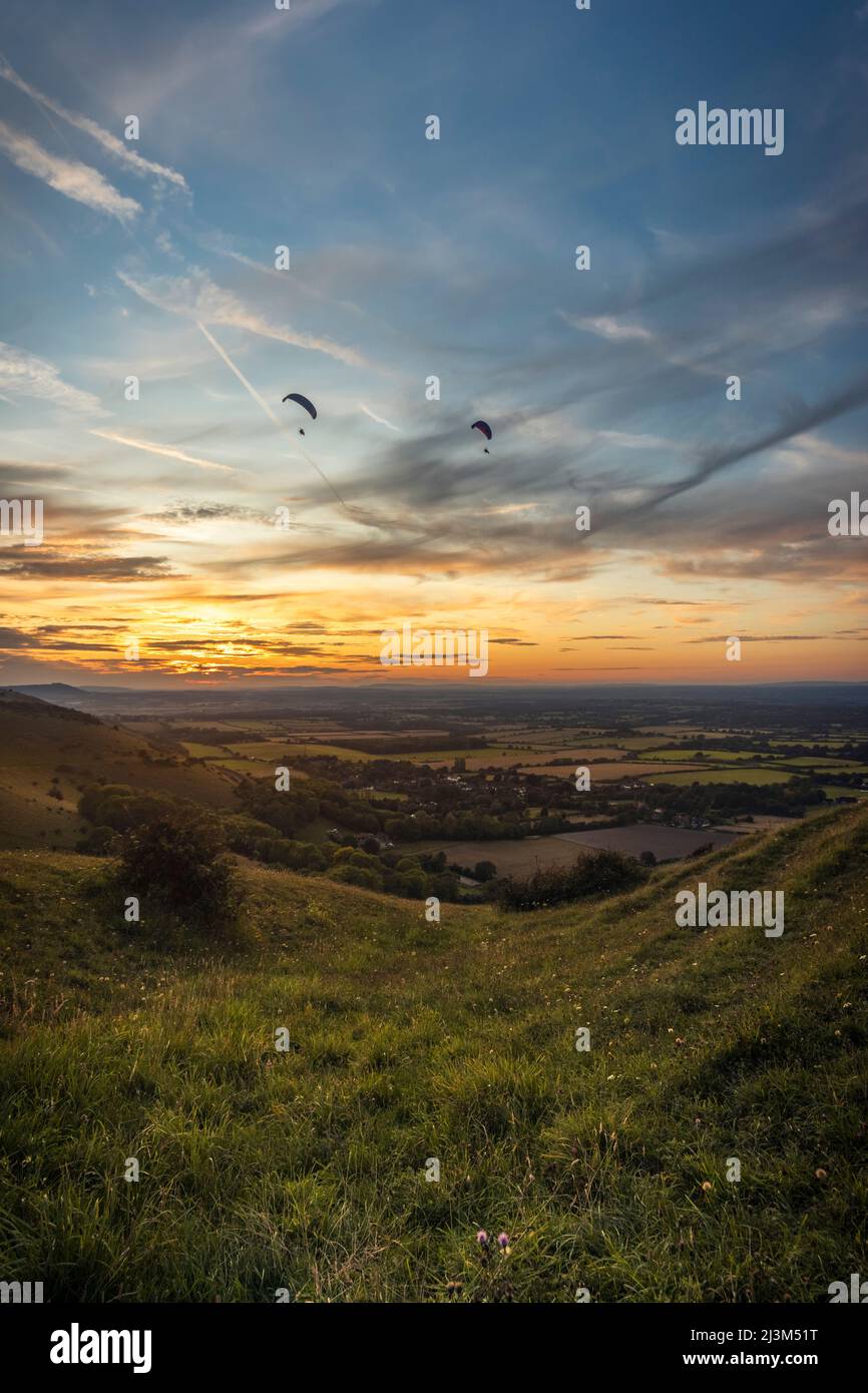 Deux parapentes survolent la campagne anglaise tandis que le soleil se couche ; Brighton, East Sussex, Angleterre Banque D'Images