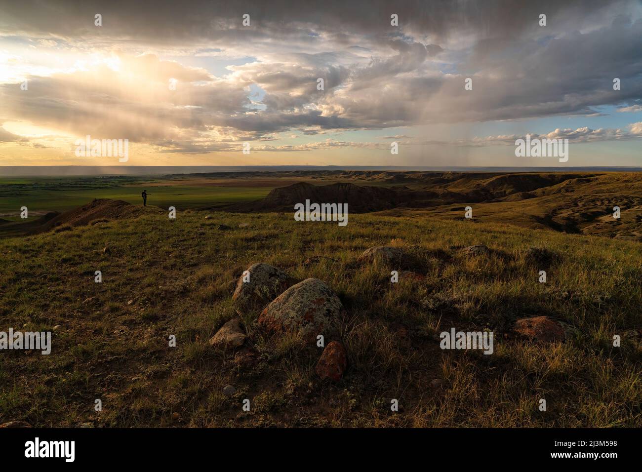 Femme debout regardant le coucher de soleil sur les prairies de la Saskatchewan; Val Marie, Saskatchewan, Canada Banque D'Images