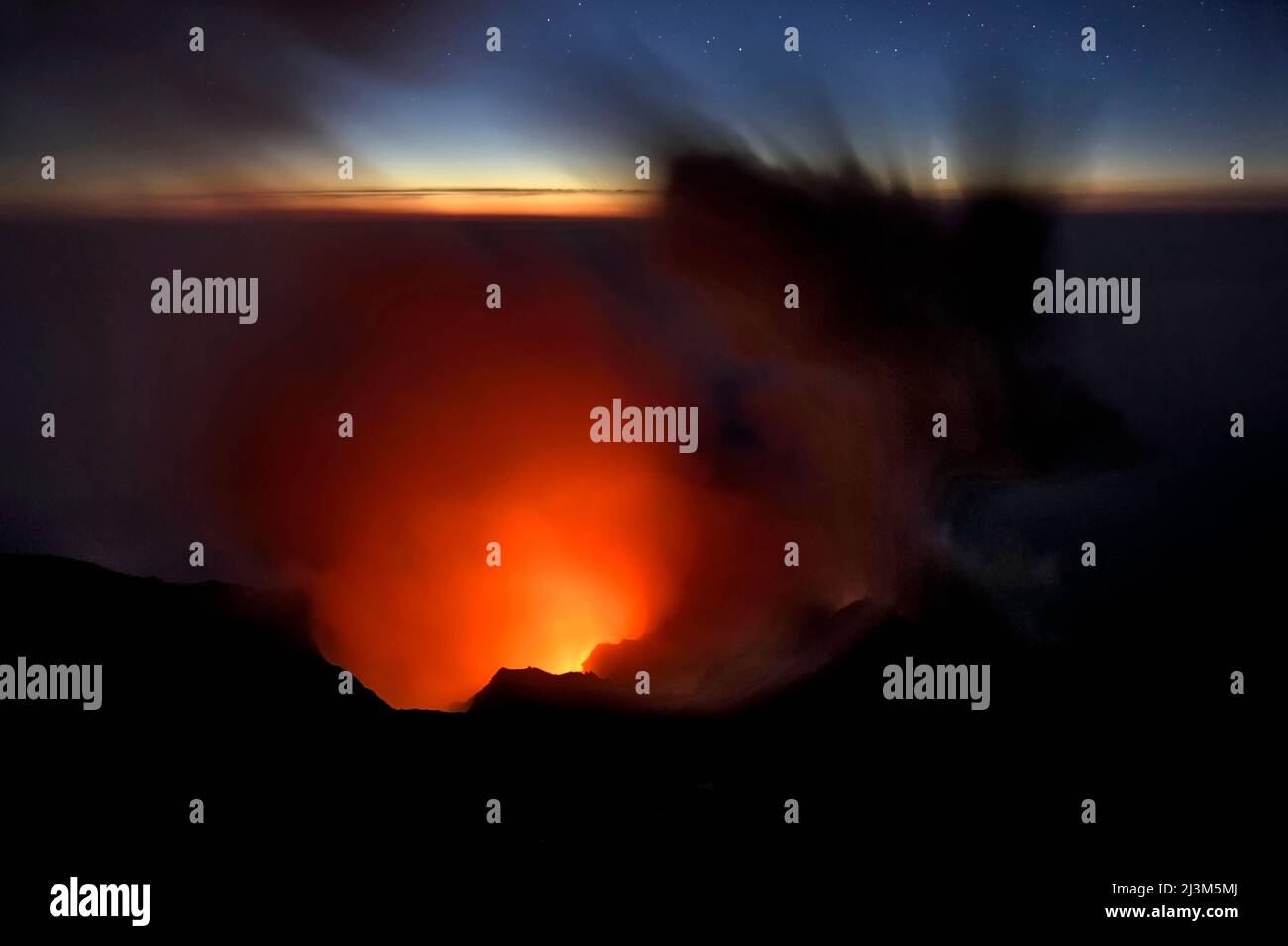 La fumée et les cendres s'élèvent d'un cratère de volcan et dans le ciel du soir.; Stromboli Island, Italie. Banque D'Images