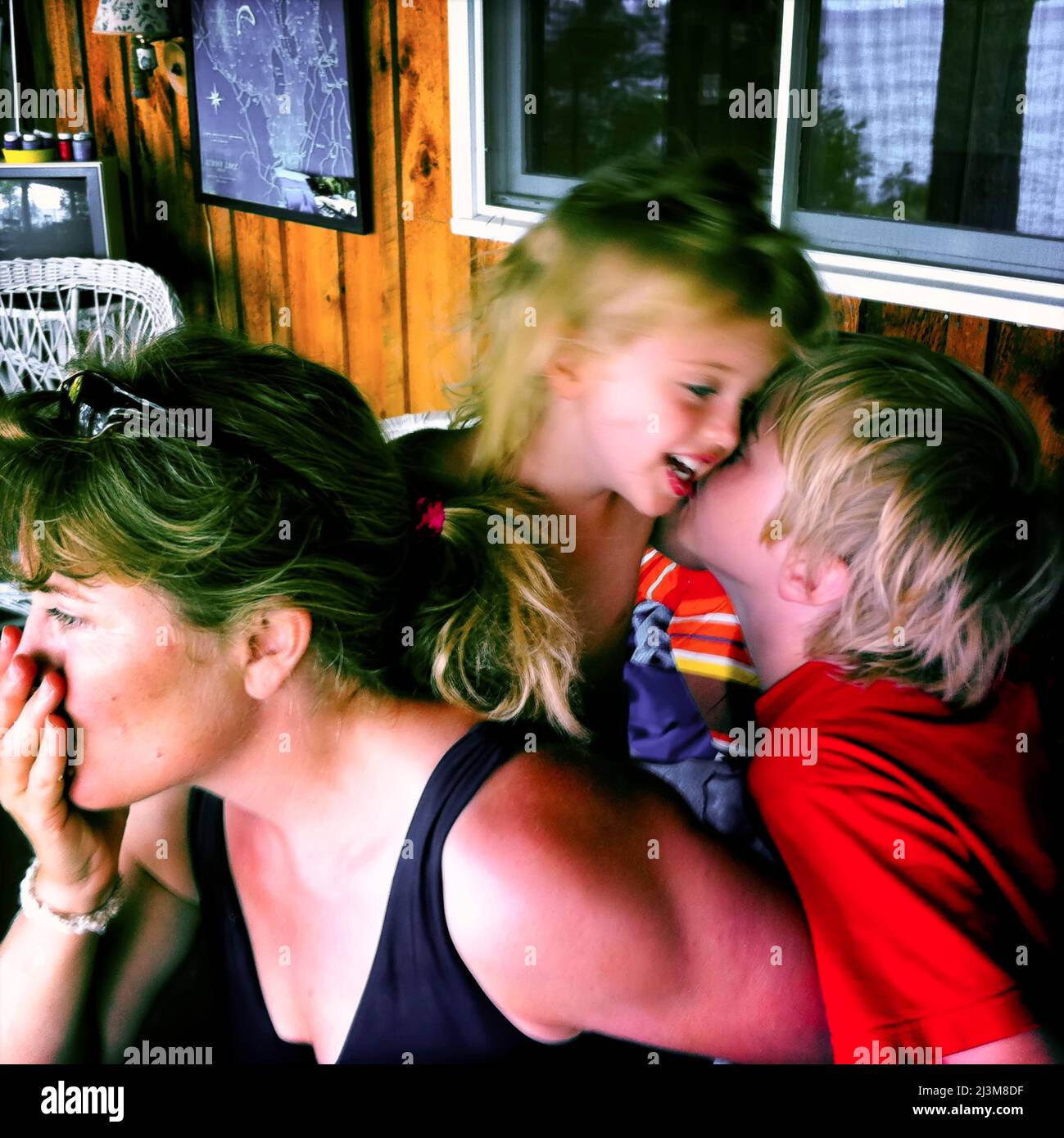 Maman fait une pause tandis que son fils de huit ans embrasse sa sœur de deux ans à Sebago Lake, Maine.; Sebago Lake, Maine, États-Unis. Banque D'Images