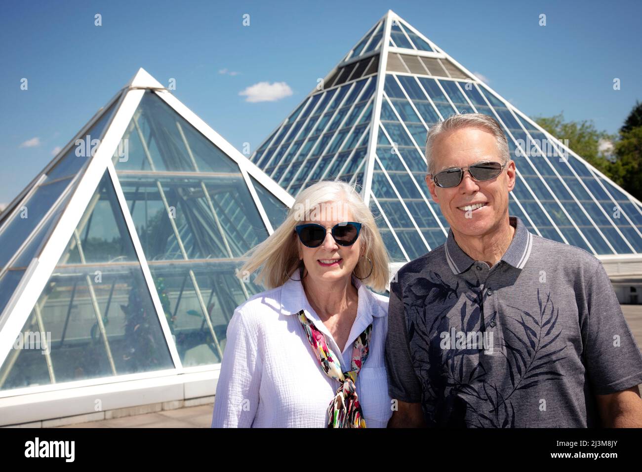 Portrait extérieur d'un couple mature portant des lunettes de soleil à l'architecture moderne dans le contexte urbain; Edmonton, Alberta, Canada Banque D'Images