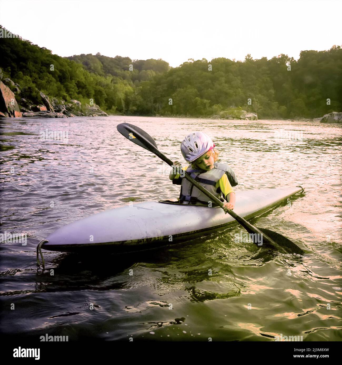 Une jeune fille de trois ans pagaie son kayak sur le fleuve Potomac.; Potomac, Maryland. Banque D'Images
