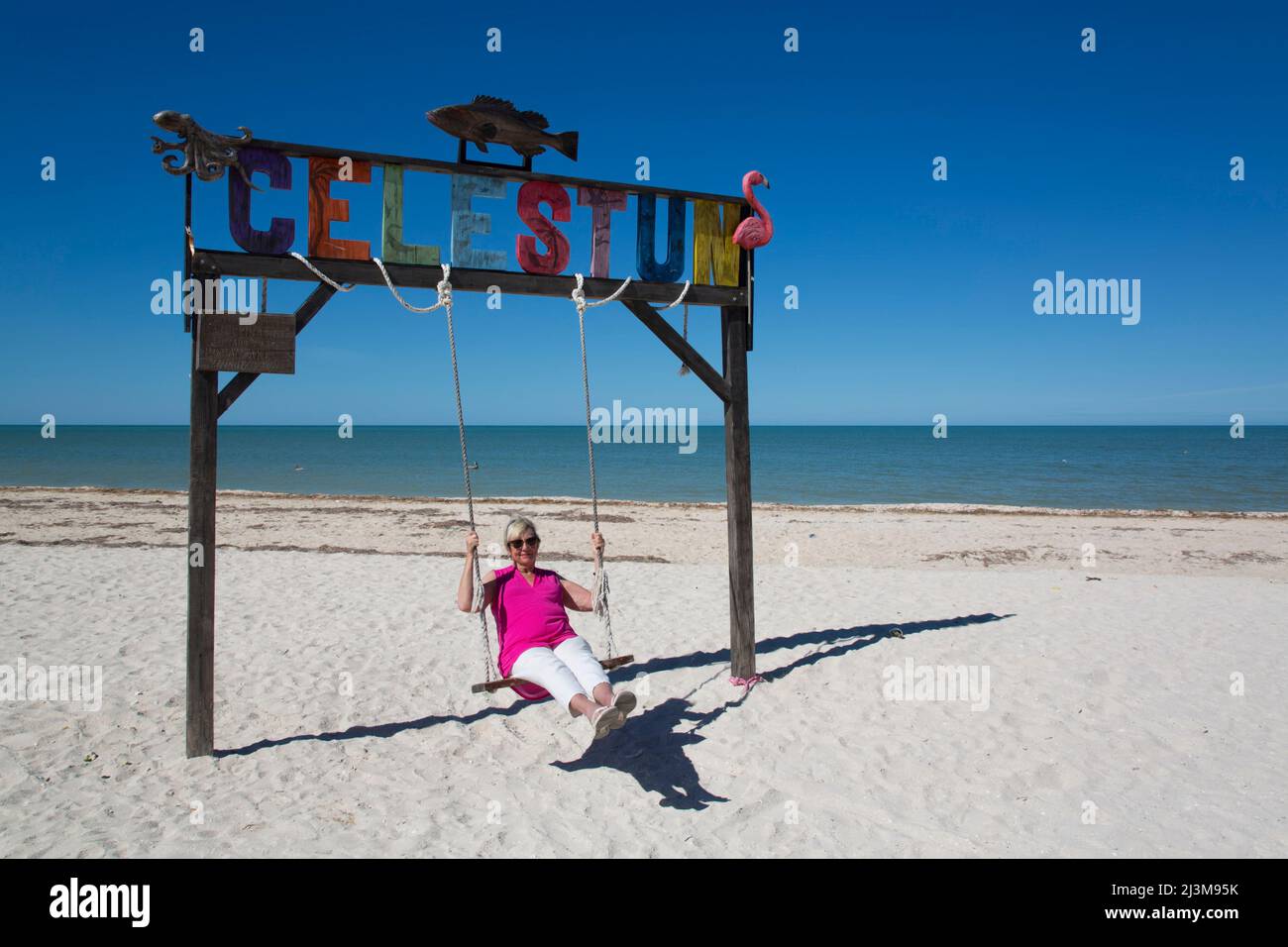 Femme sur une balançoire avec panneau Celestun sur une plage de sable blanc sur la côte du golfe du Mexique; Celestun, Yucatan State, Mexique Banque D'Images