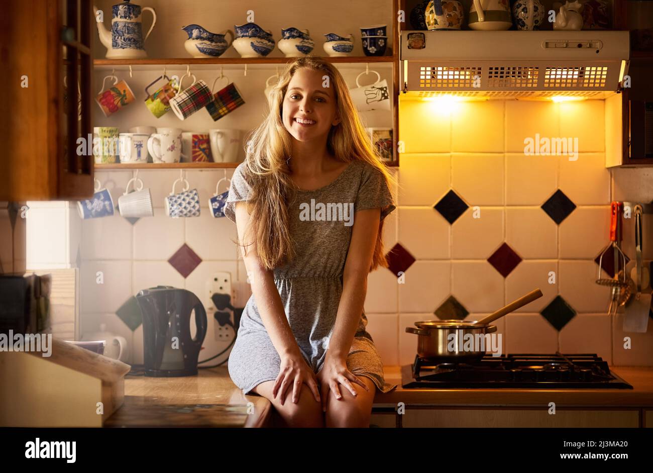 La maison pour le week-end. Portrait d'une jeune femme attrayante assise dans sa cuisine. Banque D'Images