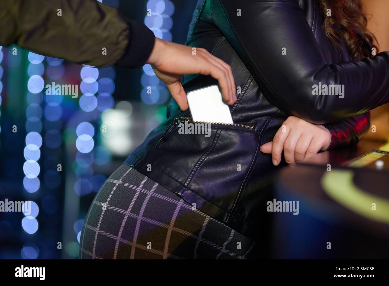 Prenez soin de vos objets de valeur. Gros plan d'un homme pickpockpocket d'un téléphone de femme de sa veste dans une boîte de nuit. Banque D'Images