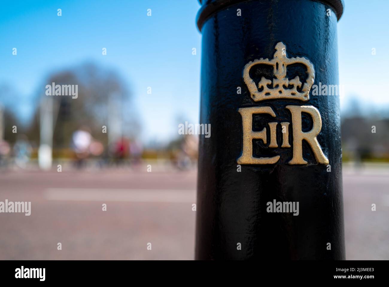 Londres, Royaume-Uni - 26 mars 2022 : bollard avec l'insigne de la reine Elizabeth 2nd à l'extérieur de Buckingham Palace, Londres. Hyde Park est visible sur un écran lumineux Banque D'Images