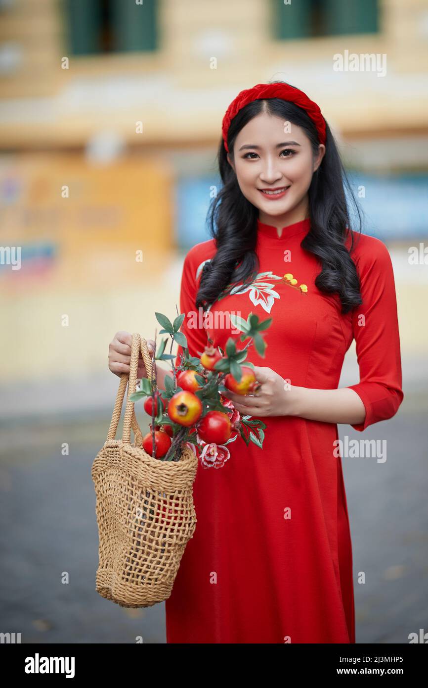 Ho Chi Minh ville, Vietnam: Portrait d'une brillante fille vietnamienne dans un rouge ao dai pour accueillir le nouvel an traditionnel vietnamien Banque D'Images