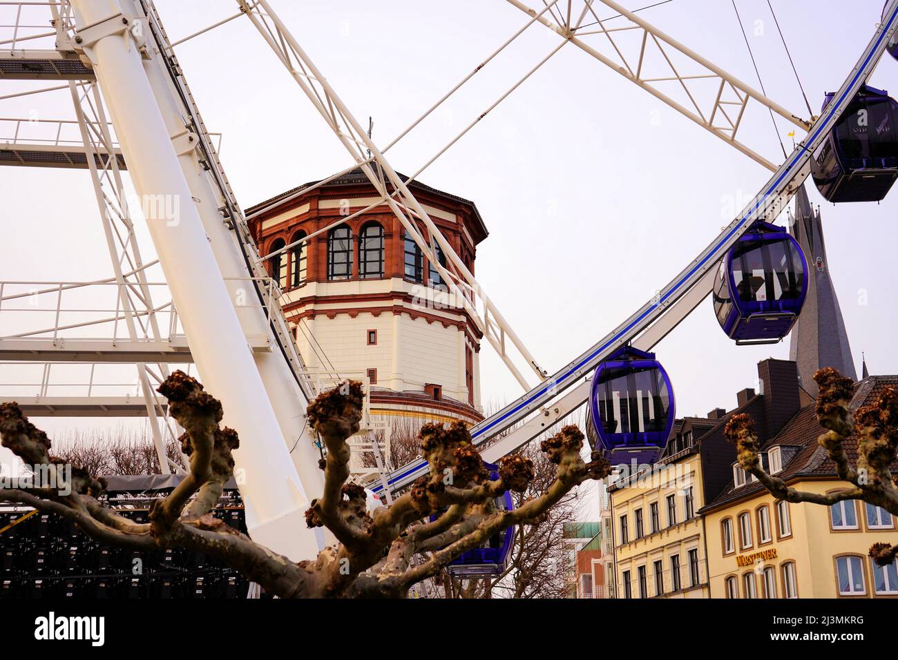 Vue rapprochée d'une grande roue dans la vieille ville de Düsseldorf près du Rhin avec tour de château historique en arrière-plan. Banque D'Images